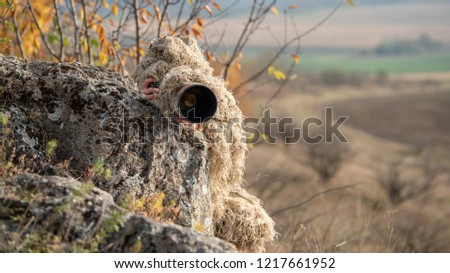 Camouflage wildlife photographer in the ghillie suit working in the wild