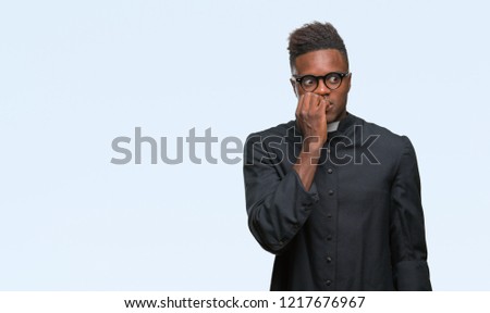 Young african american priest man over isolated background looking stressed and nervous with hands on mouth biting nails. Anxiety problem.