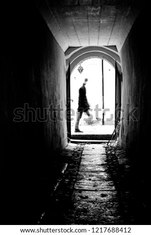 Silhouette of man at the end of the tunnel. Black and white rough street photography.