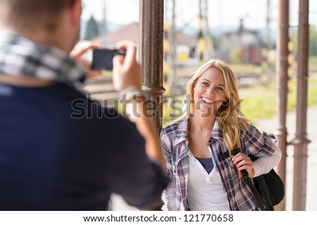 Woman smiling man taking her picture vacation backpack railroad camera