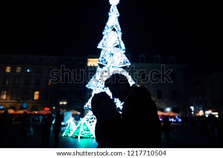 A silhouette of couple with a new year tree on background