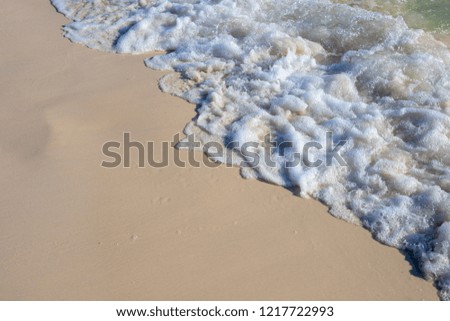 Foamy sea tide on white sand beach. Sea wave on smooth sand. Tropical seaside in sunlight photo. Marine holiday. Seashore landscape. Exotic island vacation banner template. Sea tide on smooth sand