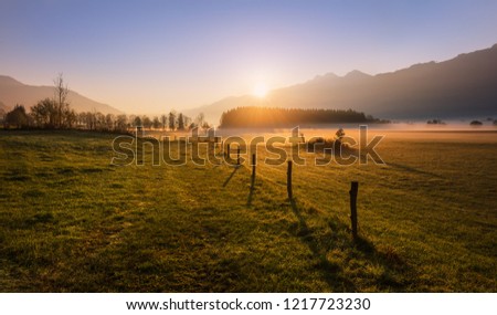 Autumn sunrise in the alpine mountains. Morning sunshine illuminates the Alpine valley with fog. 
