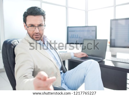 businessman sitting at his Desk and pointing at you