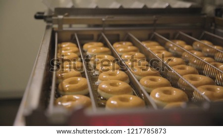 Procedure of making donuts in a small town donut bakery - donuts frying in a deep fryer. Scene. Process of preparation of donuts Royalty-Free Stock Photo #1217785873