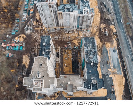 Aerial or top view from above, construction of modern houses or buildings with cranes and other industrial vehicles among city architecture, toned