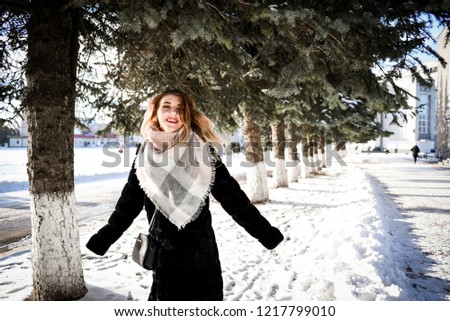 beautiful girl with long, bright hair in a black coat, walking in a winter city