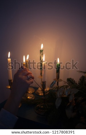 Christmas decoration with burning candles and christmas tree branches. Vintage style toned picture. Woman lights candles
