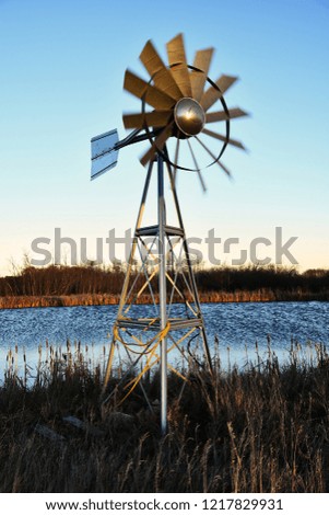 An image of an old metal agricultural windmill at dusk. 