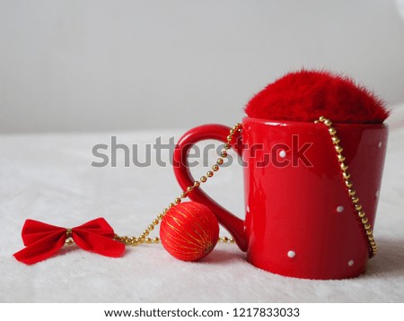 Red cup with fluffy cover, bauble and bow. Close up