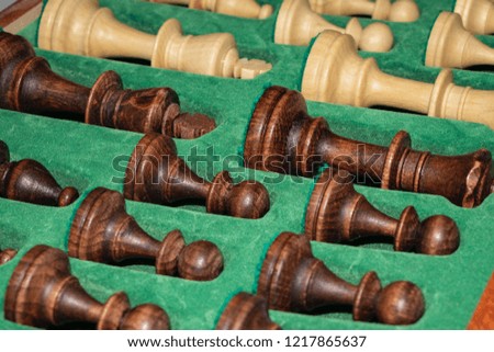 wooden chess pieces (white / black) are neatly folded in a box with a green background