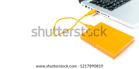 Close up of external hard disk drive for connect to laptop, transfer or backup data between computer and HDD. Orange hard disc for backup files and important information using USB 3.0 connection