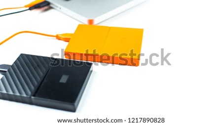 Close up of external hard disk drive for connect to laptop, transfer or backup data between computer and HDD. Orange hard disc for backup files and important information using USB 3.0 connection
