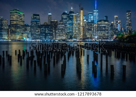 View of Manhattan over the East River with piles in the shadow. 