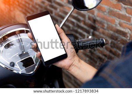 Mockup image of woman sitting on the motorcycle, hand holding mobile smartphone with blank white screen . clipping path.