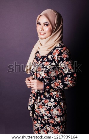 A young female wearing hijab gives a welcoming and friendly hand sign