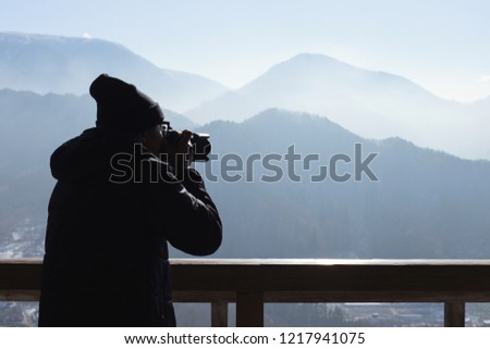 Young man standing take photograph on top of a hill with sunlight winter in Japan. Travel Concept