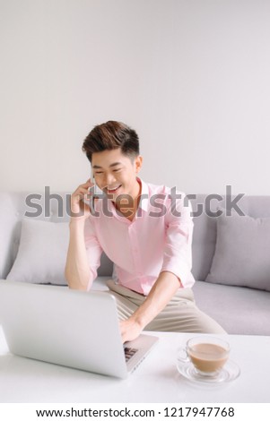 Young handsome asian man with laptop on the phone