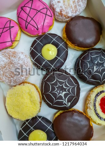 Picture of assorted donuts in a box with chocolate frosted, pink glazed and sprinkles donuts.
Colorful donuts , Top view.