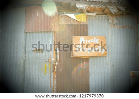 Board sign on rusted tin wall with private property in hand writing text 