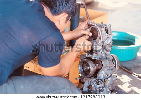 Mechanic working with with motorcycle engine.