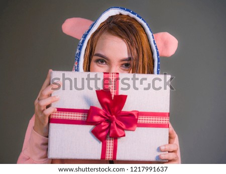 young happy and beautiful woman in winter warm hoodie holding Christmas or birthday present box with ribbon in her hands smiling cheerful and excited celebrating holiday or anniversary