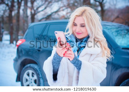 Winter holiday concept. Inspiration and fairy cold time. Woman in fashionable dress and fur coat at park take a selfie . Pretty nice lady outdoor, holiday days, snowy magical christmas time