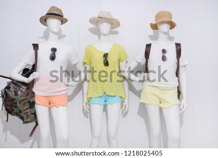 Three mannequin in female shirt with blue ,yellow ,orange shorts trousers jeans, handbag ,sunglasses ,bag isolated

