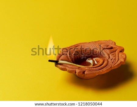 Tradition Indian terracotta oil lamp on bright yellow background. Indian festive object. Isolated Indian lamp on isolated background.
