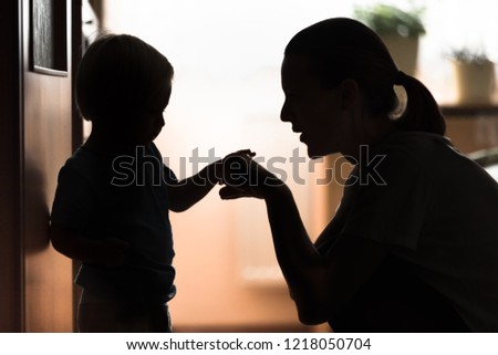 Mother playing game with her one year old son at home. 