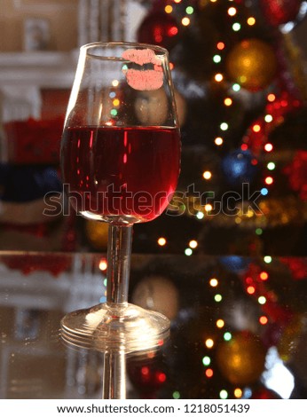 A glass is filled with red wine on the background of a decorated Christmas tree