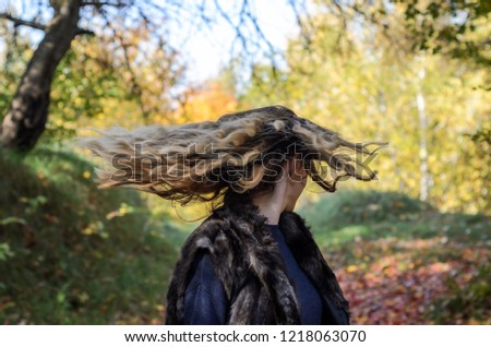 Young beautiful girl with long hair walks in the autumn forest