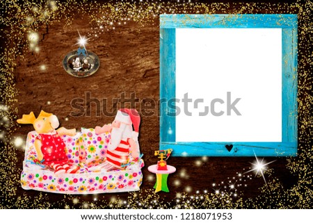 Christmas photo frame card. Santa Claus and the reindeer sitting on a sofa next to the phone and the Christmas tree on wooden background and with an empty frame for photos or messages
