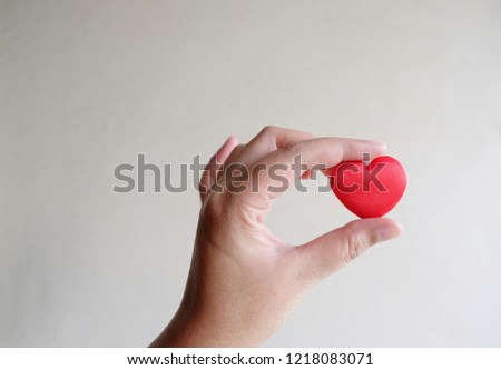 Concept of love, hand holding red heart shape on concrete wall background, sharing love for everyone
