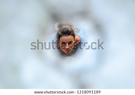 A young girl looks up through the hole