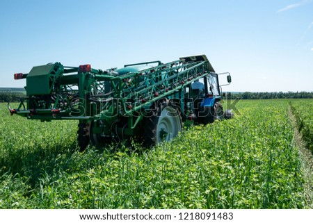 blue tractor in the field with blue sky is preparing for spraying and chemical treatment of plants