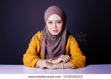 Smiling girl in hijab covering her eyes with happiness