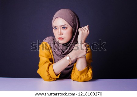 Smiling girl in hijab covering her eyes with happiness