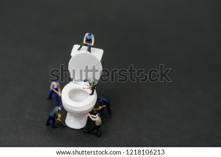 Miniature people :Plumber repairing toilet and change White Toilet Bowl and Flush Installation.Septic and Sanitary Residential Systems.Black background.