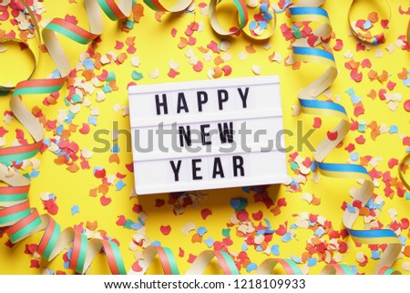 happy new year party celebration flat lay with confetti and streamers on yellow background