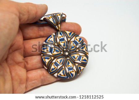 Mandala ethnic pendant isolated in woman hand. Handmade jewelry of polymer clay. Winter necklace.