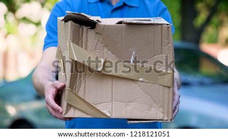 Male courier showing damaged box, cheap parcel delivery, poor shipment quality Royalty-Free Stock Photo #1218121051