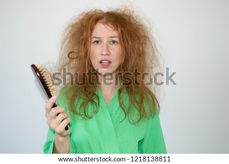 girl in a bathrobe with tangled hair looks into the camera on a white background