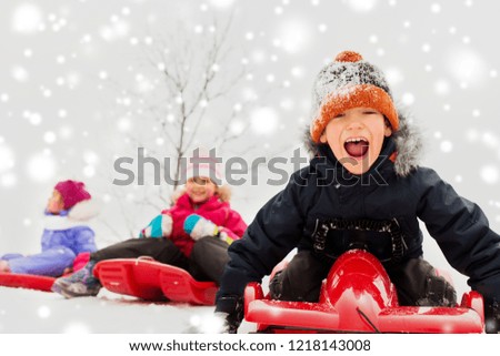 childhood, sledging and season concept - group of happy little kids sliding on sleds in winter