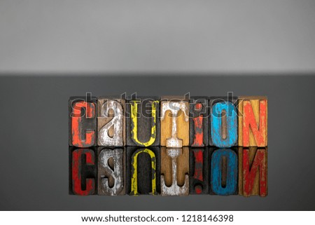 caution word from colored wooden letters on gray background