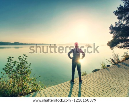 Male runner exercising on footpath at coast of island. Beach at sunset with sun in the background. Vintage effect style pictures.