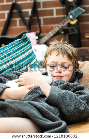 A little boy with ADHD, Autism, Aspergers Syndrome cuddles his pet rabbit, bonding, caring and kind