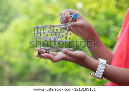 Young girl holding a shopping cart on a blurred green background. Business concept.