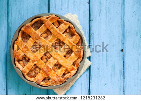 Top view of golden apple pie with cinnamon on blue wooden background