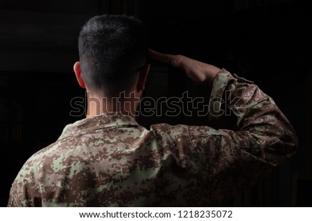 US Army. Young soldier saluting standing on black background
